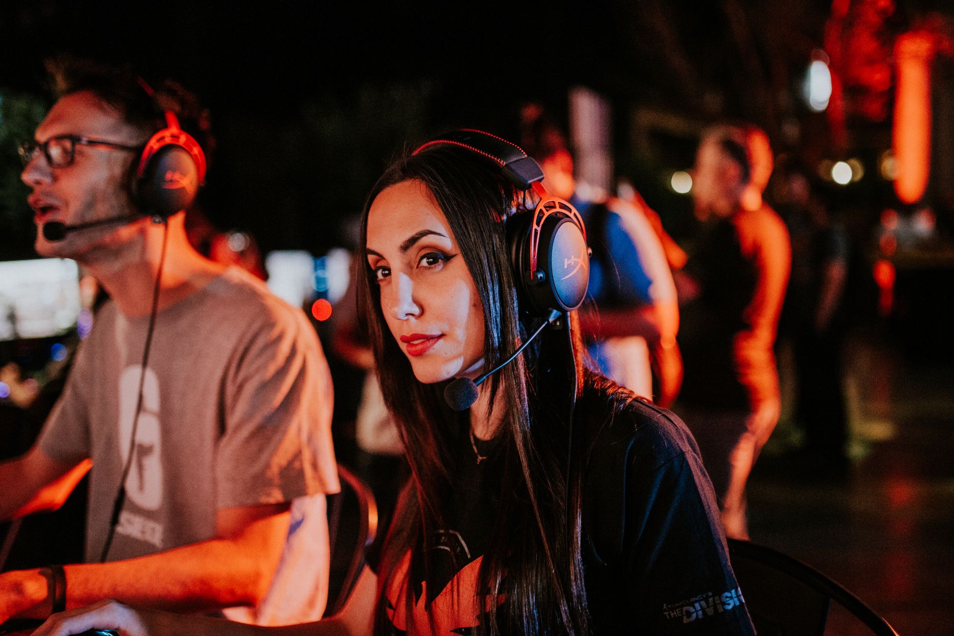 Woman gaming in esports tournament, wearing headset with focused expression, dimmed indoor lighting. — AT99: A Leader in Onli
