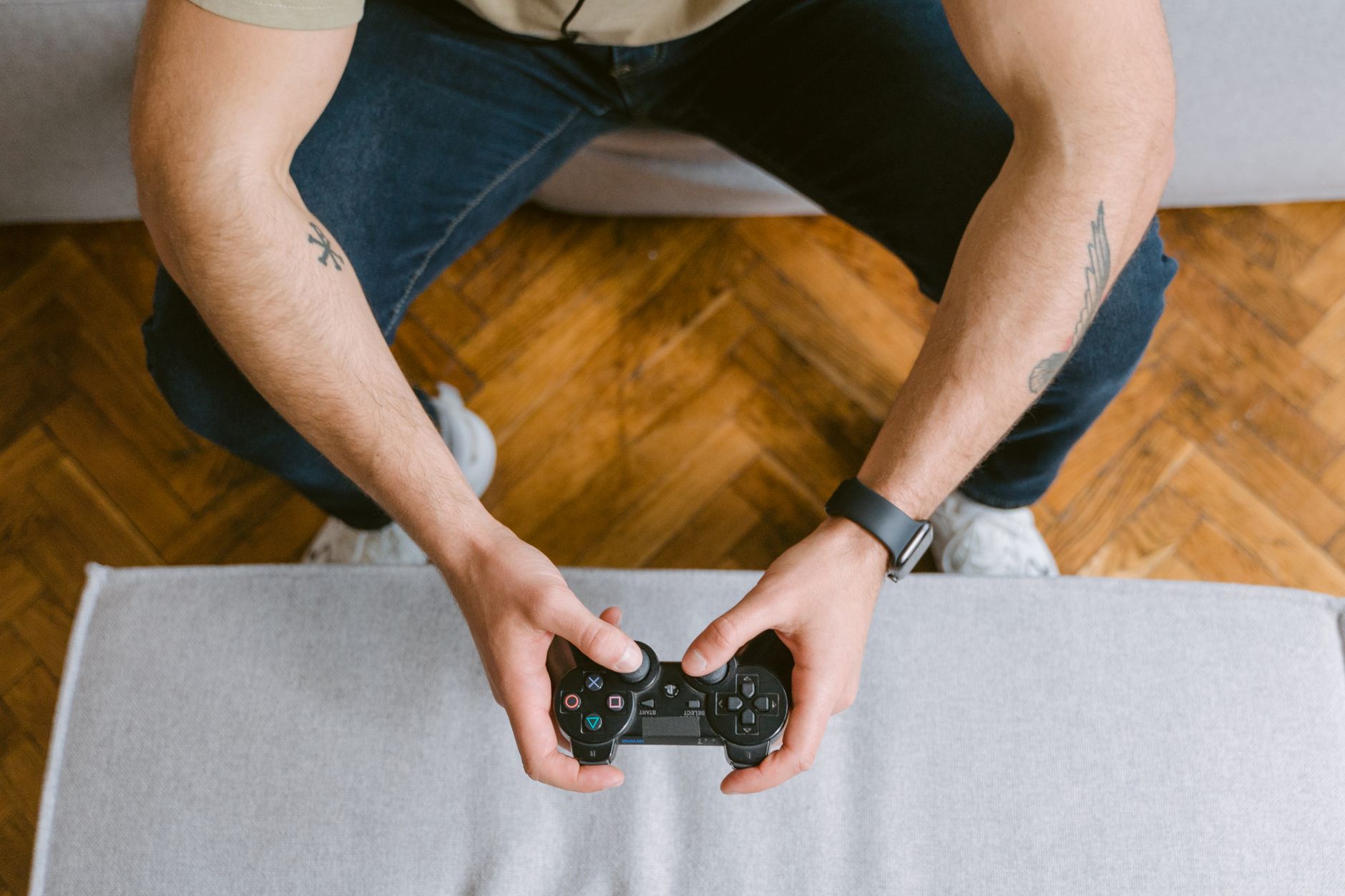 A man sitting on a couch holds a game controller, ready to play video games. — Blackjack Online Australia Providing Convenien