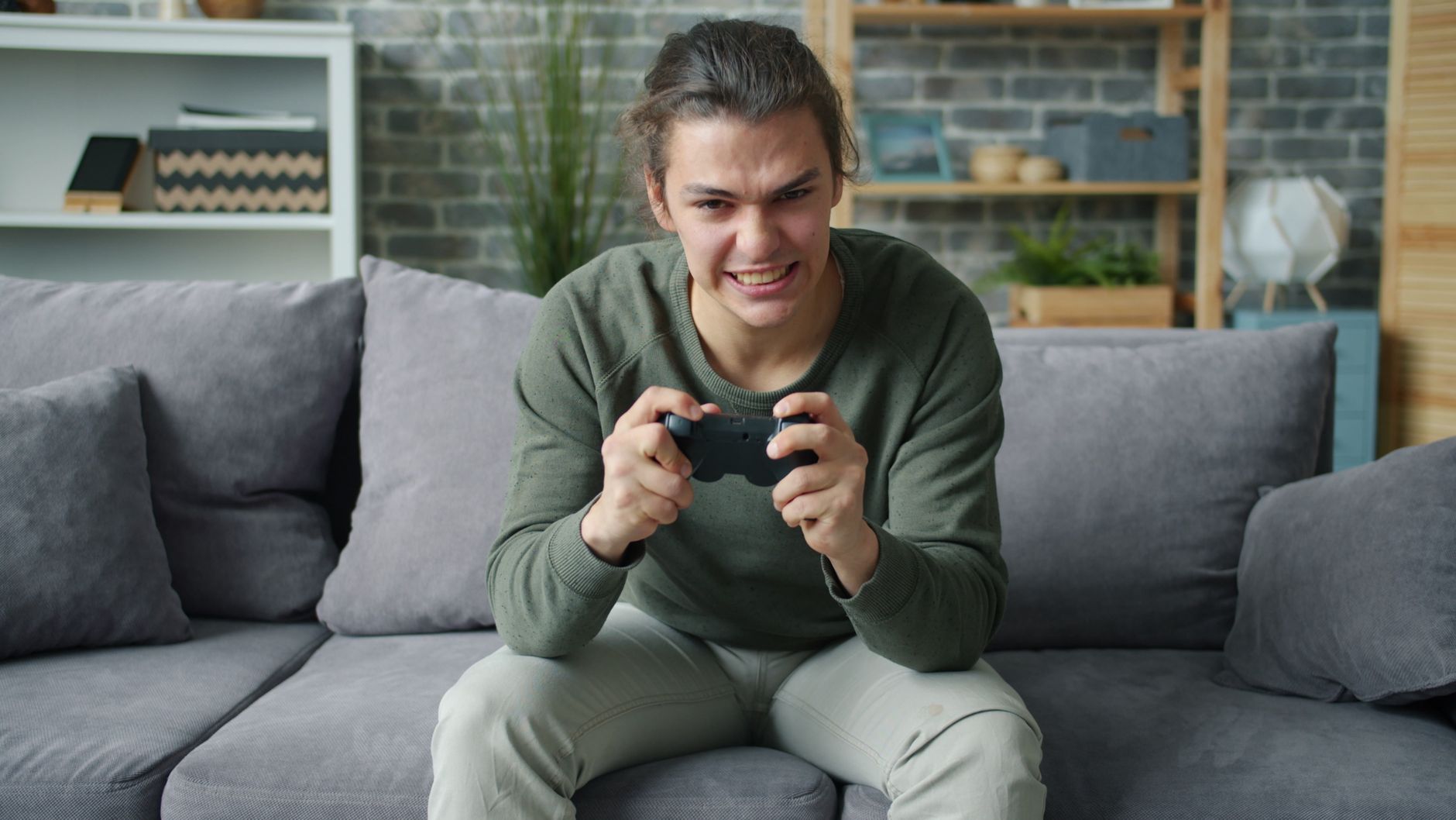 Young adult intensely playing video games on a couch in a cozy living room setting. — Casino Online Platform Delivering Immer