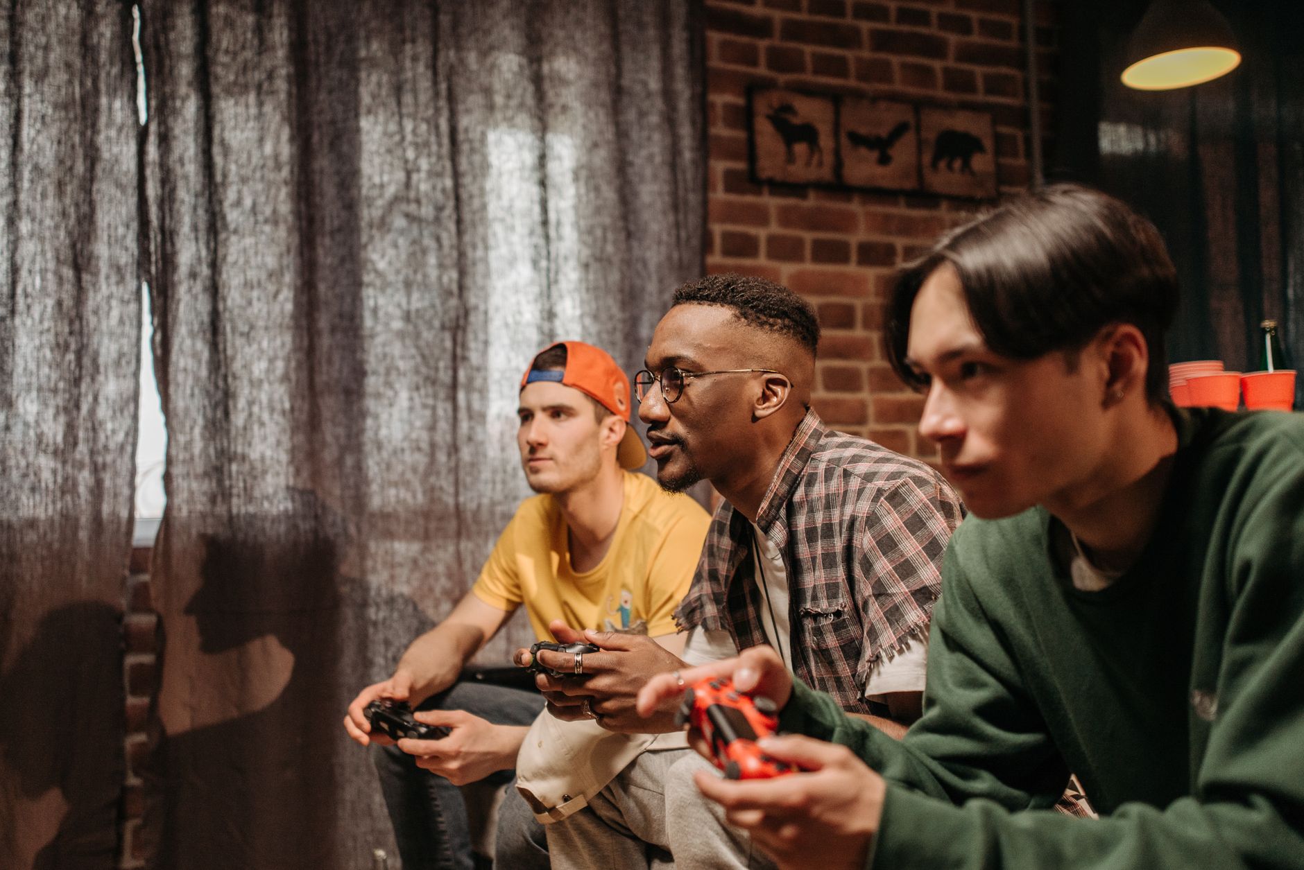 Three men focused on playing video games with controllers indoors. — Discover Exciting Games and Big Wins at Arena333 Casino