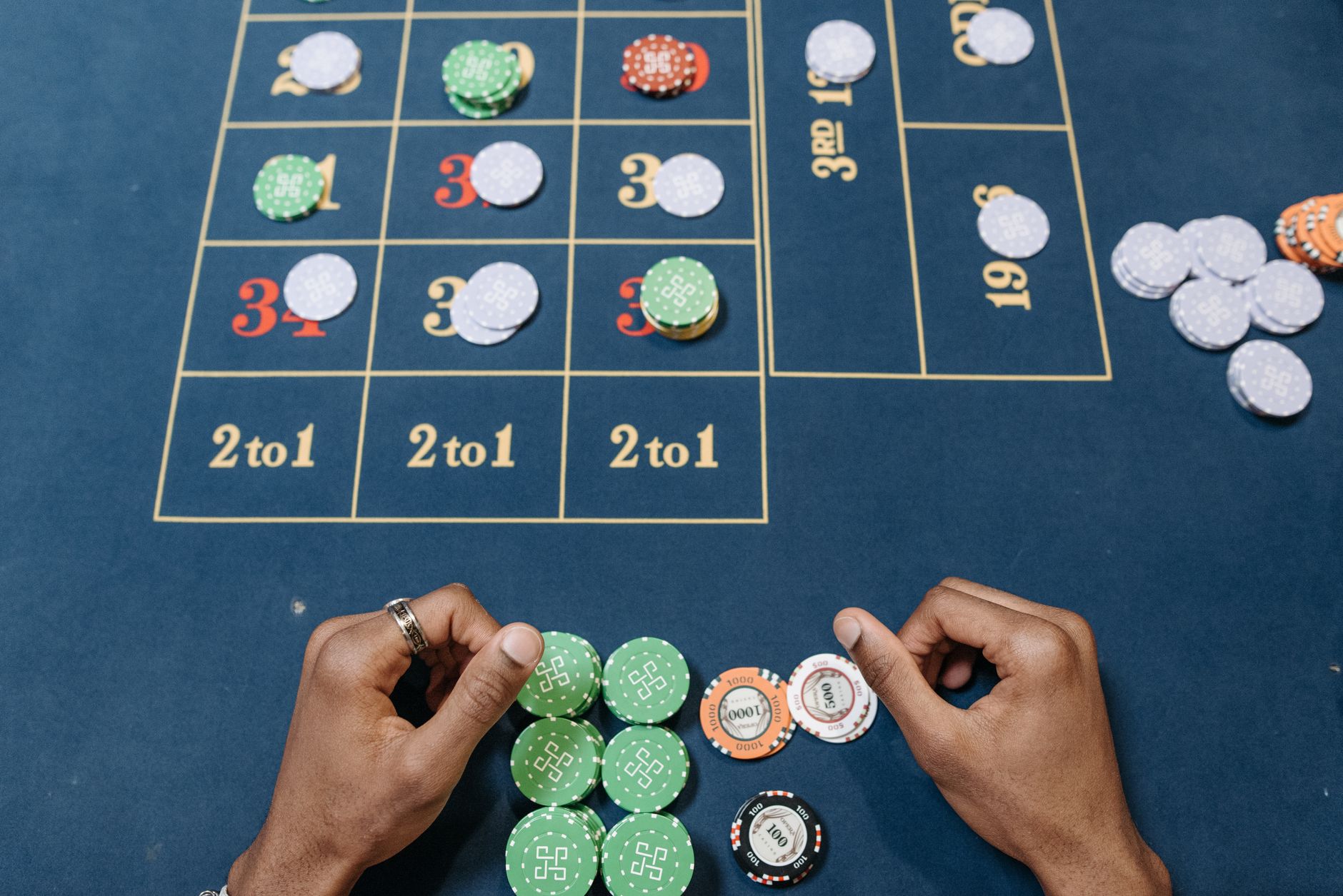 Hands arranging poker chips on a colorful casino gaming table, top view. — Discover the Unique Appeal of No Commission Baccar
