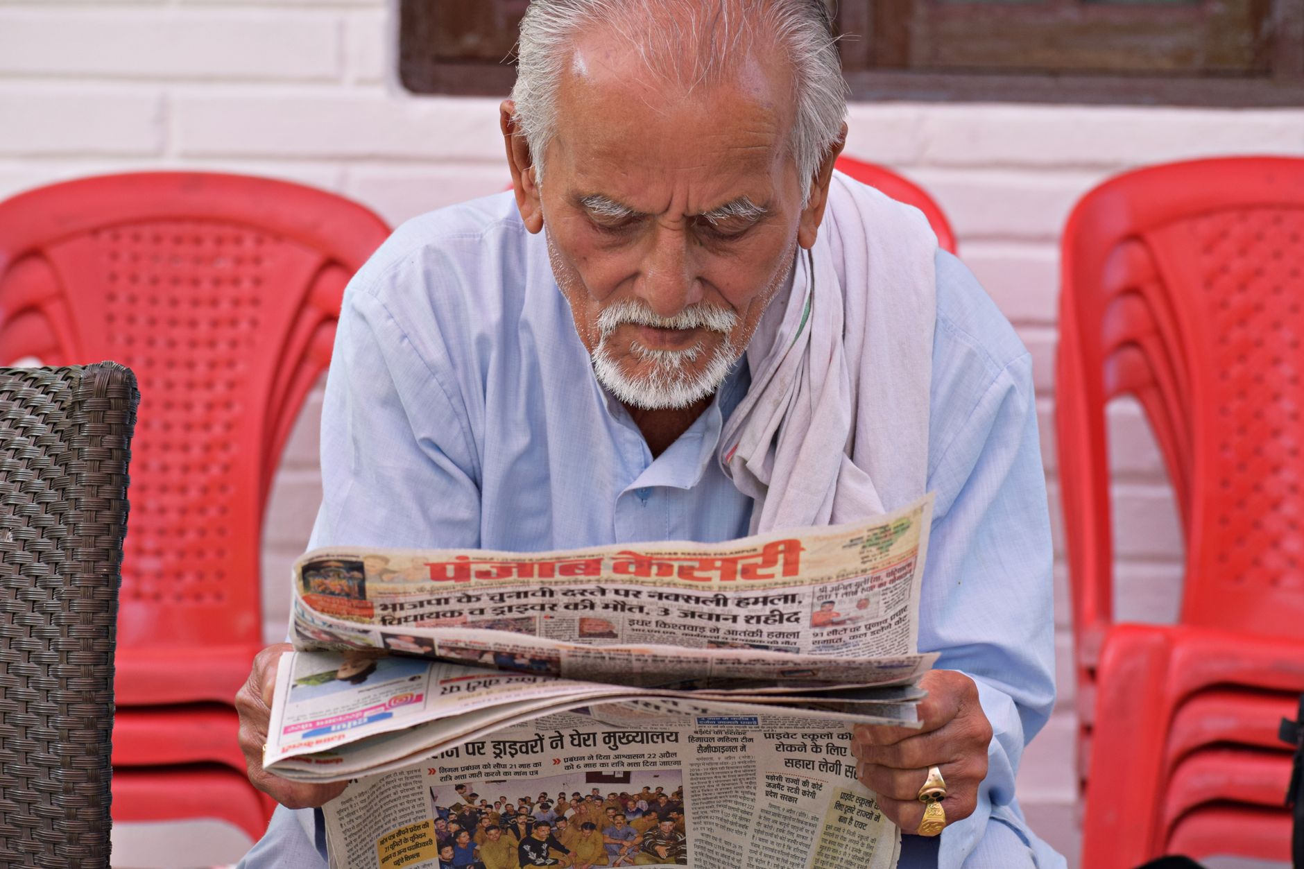 Elderly man engaging in daily reading of a newspaper while seated outdoors. — "Enter the World of Convenience with Online Lot