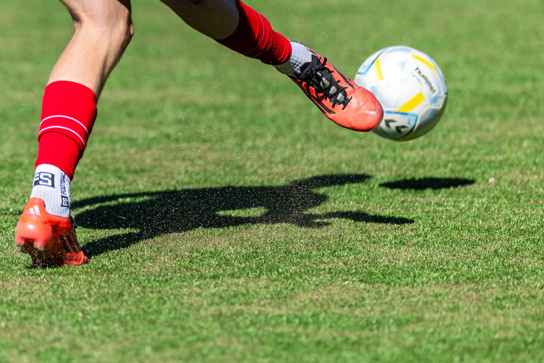 Soccer player in red kicks a ball mid-air on a sunny day outdoor field. — Entertainment City Online Betting: The Best Games t