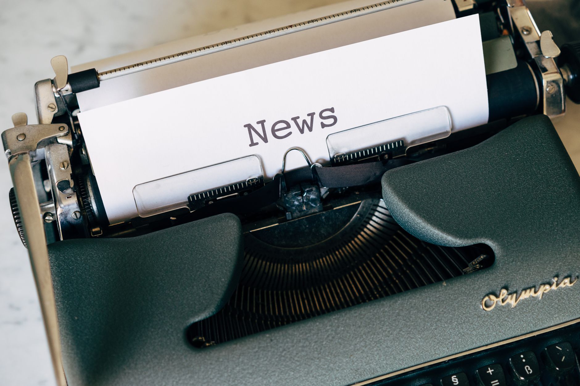 Close-up of a vintage Olympia typewriter with paper reading 'news'. Perfect for classic journalism themes. — Exploring the Be