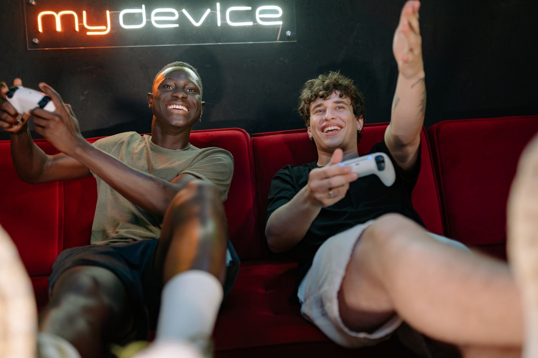 Two friends having fun and playing video games on a couch indoors. — Fishin Frenzy Casino Games Deliver Simple Gameplay With