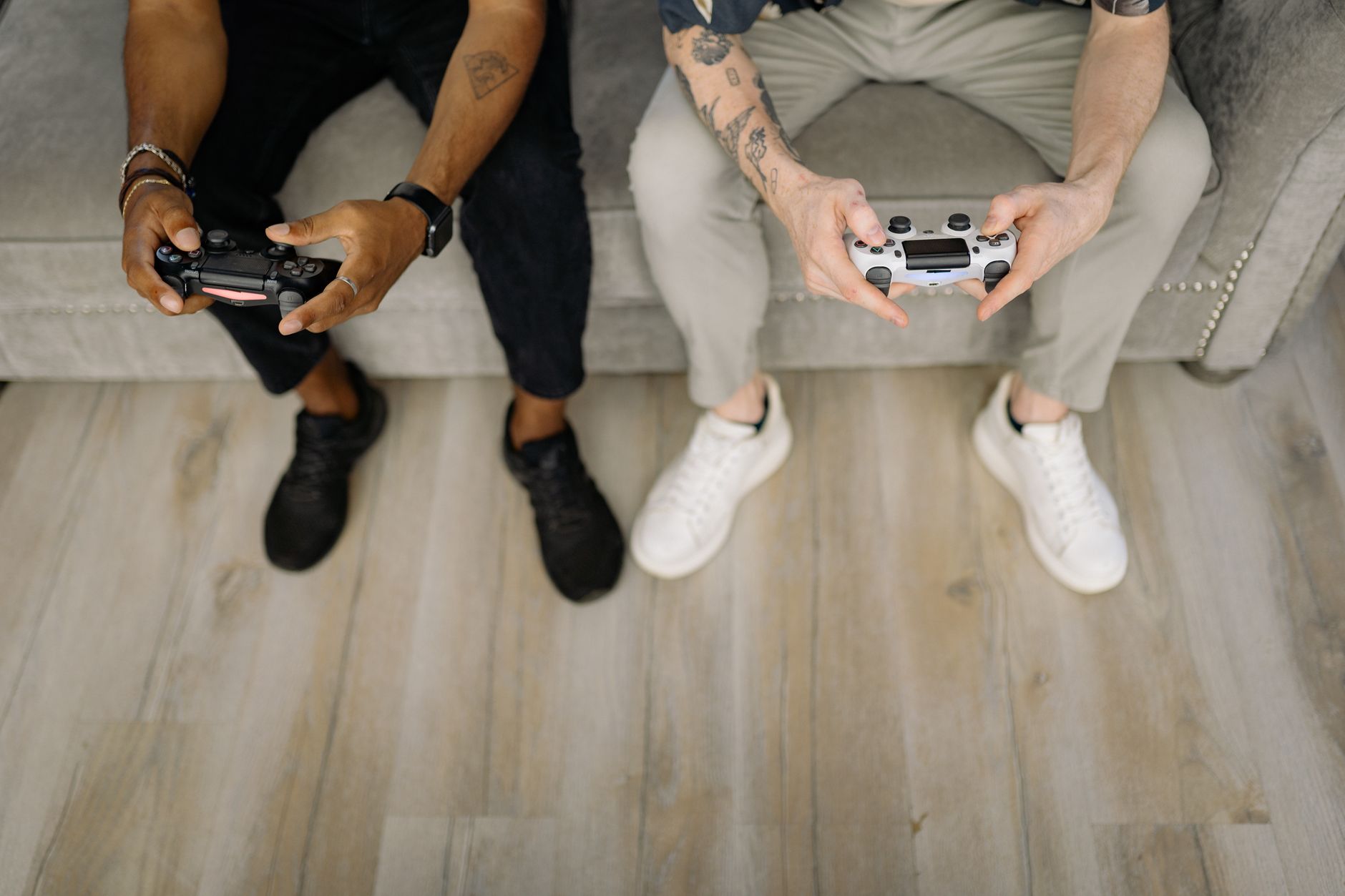 Two friends with gaming controllers focusing on a video game indoors from above. — Flexibility in Leisure Activities with Hay