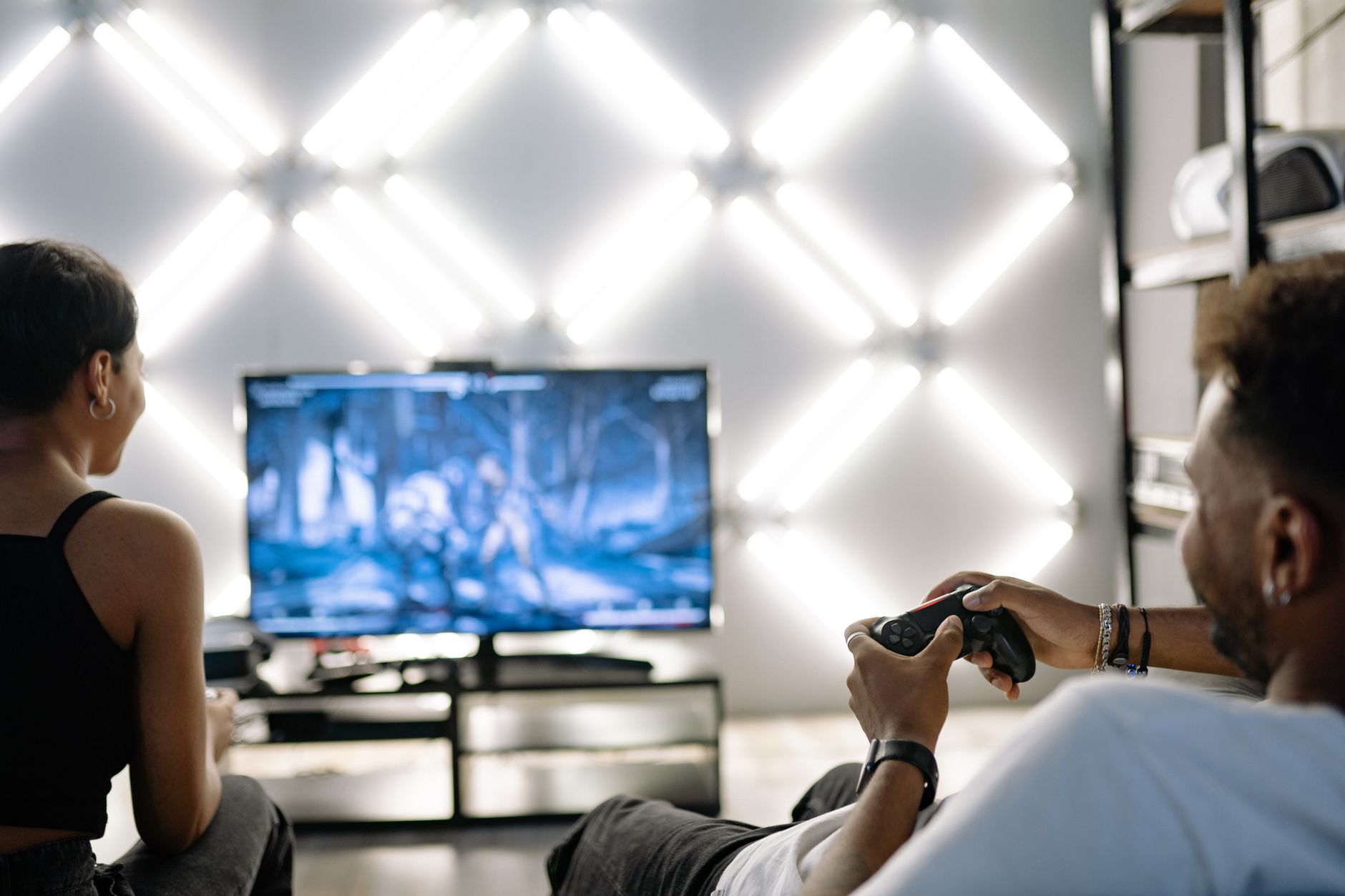 Two adults are having fun playing video games in a stylish, modern living room with LED lighting. — How MPO007 Login Ensures