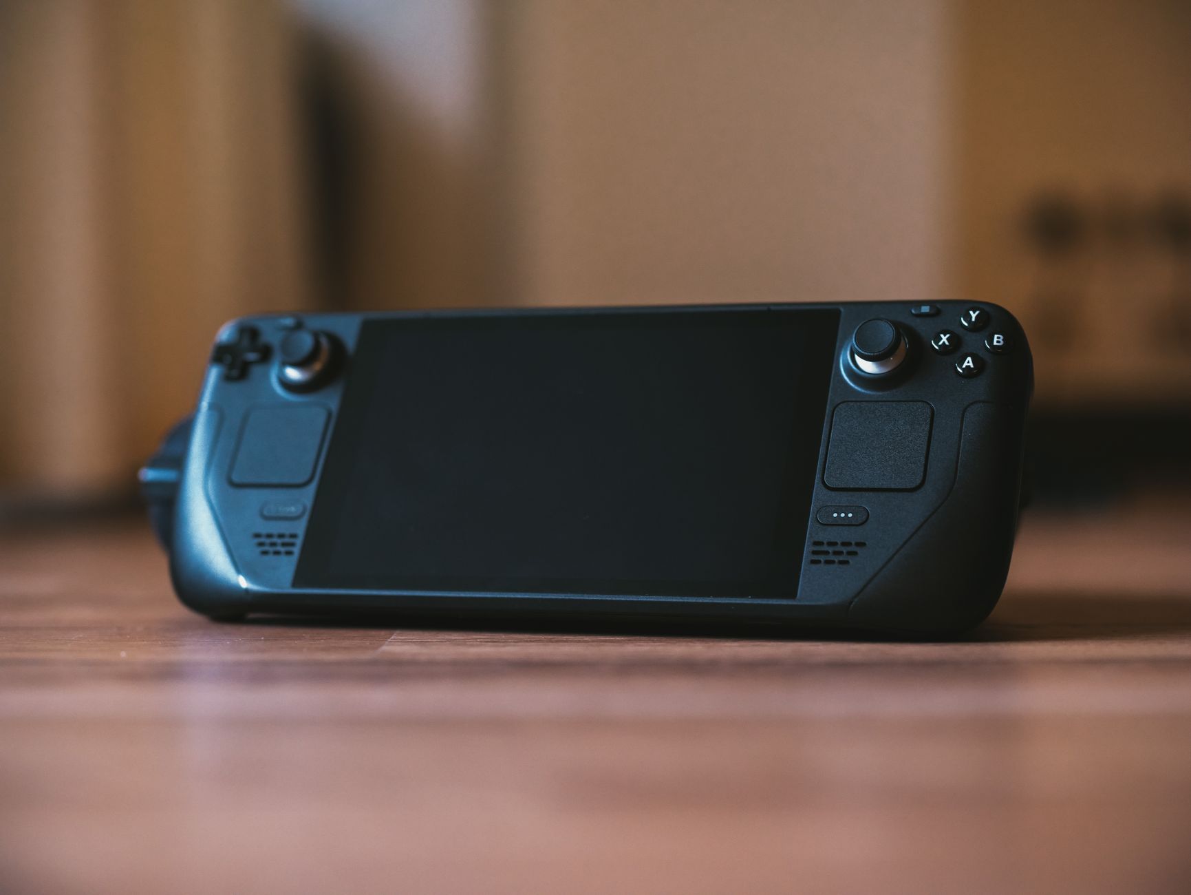 Modern handheld gaming console with buttons and joystick on a wooden surface, ideal for portable gaming enthusiasts. — How QQ