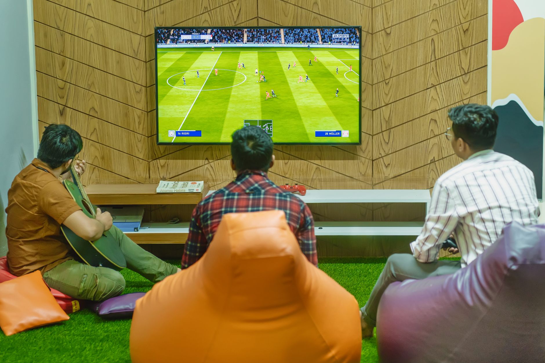 Three friends relaxing and playing a soccer video game indoors on a comfortable game night. — How Usaha188 Combines Classic C