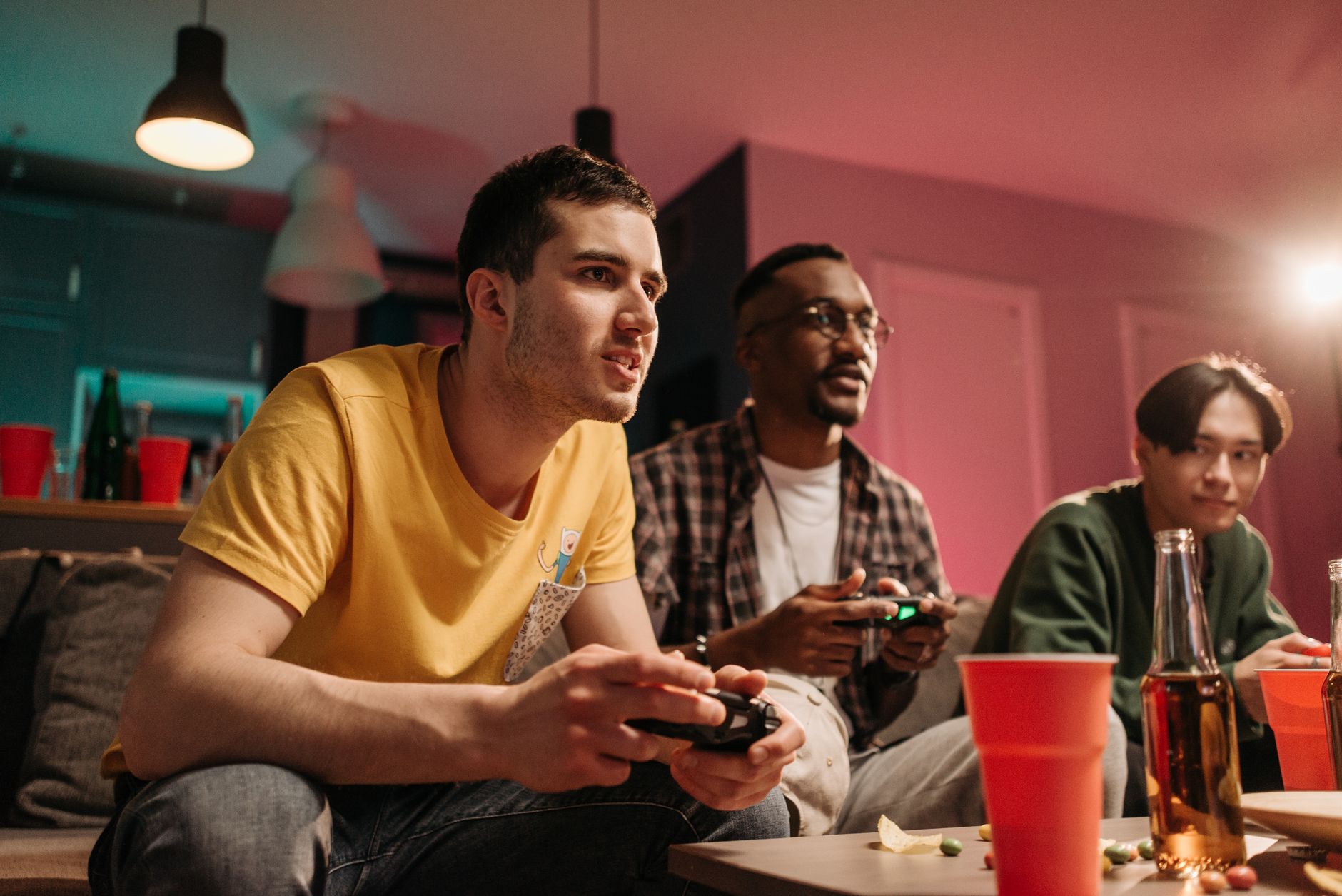 Diverse group of young adults playing video games on a cozy sofa with refreshments. — Slots Tournaments and Promotions Design