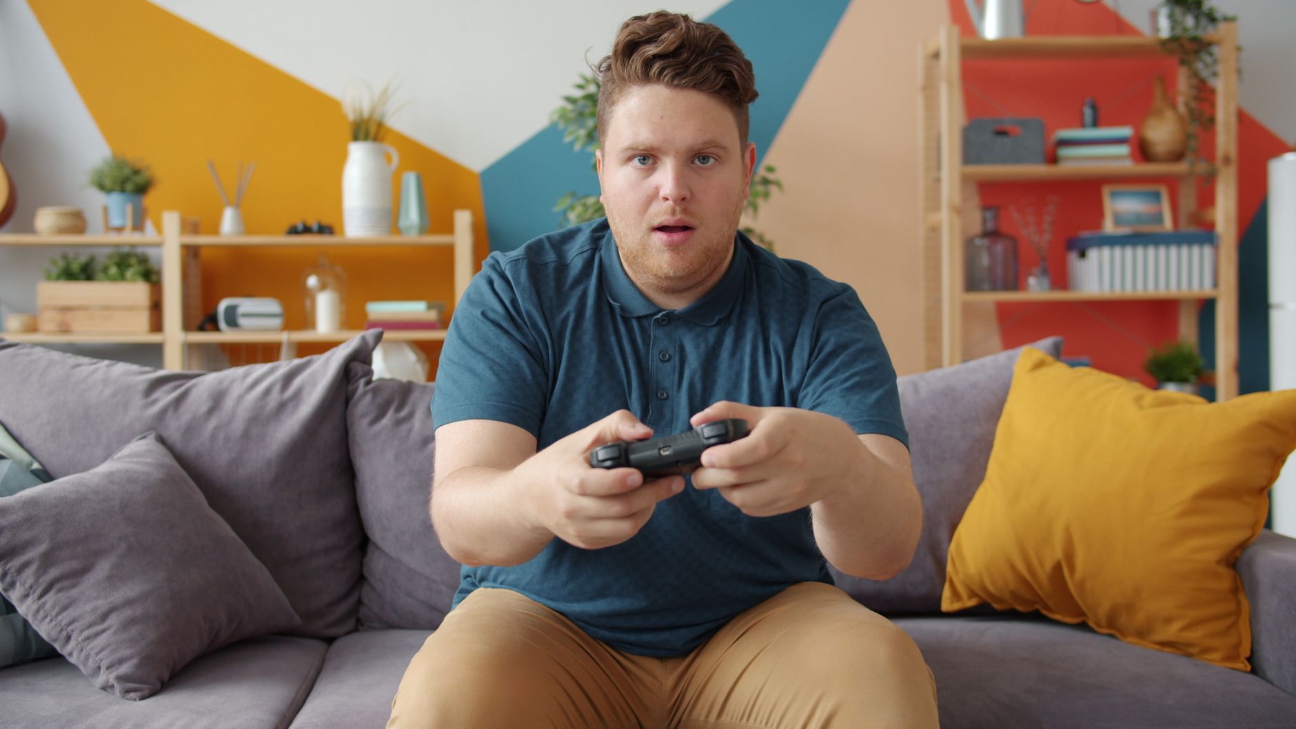 A young man intensely playing video games in a modern living room setting. — The Latest Updates and Games on pg88