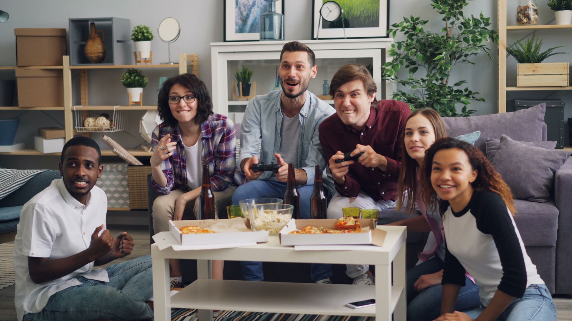 A diverse group of friends having fun playing video games indoors, surrounded by pizza and drinks. — Top Platforms to Play Se