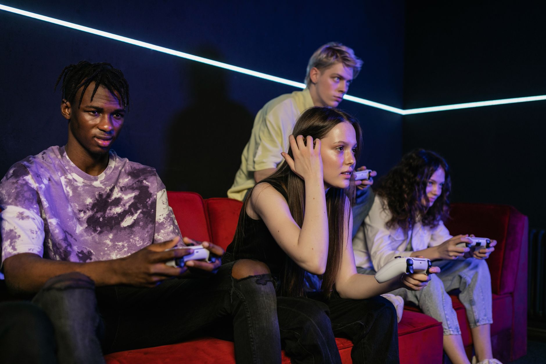 Group of friends enjoying a gaming session on a red sofa with wireless controllers. — Understanding scatter symbols and their